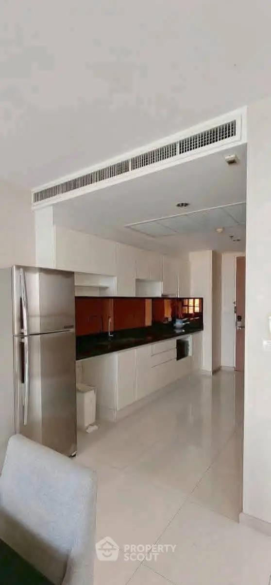 Modern kitchen with sleek cabinetry and stainless steel fridge in a contemporary apartment.