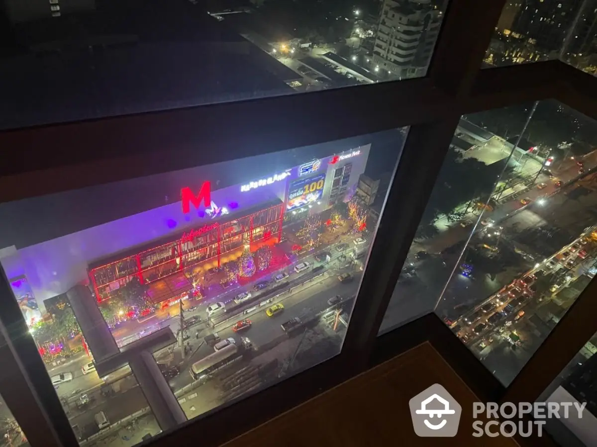 Stunning city view from high-rise building window at night with vibrant lights.