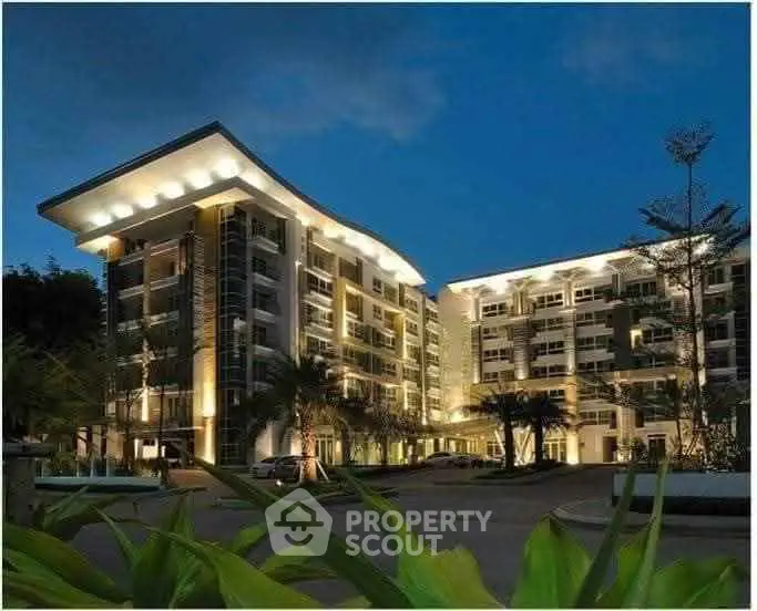 Stunning modern apartment building with elegant night lighting and lush landscaping.