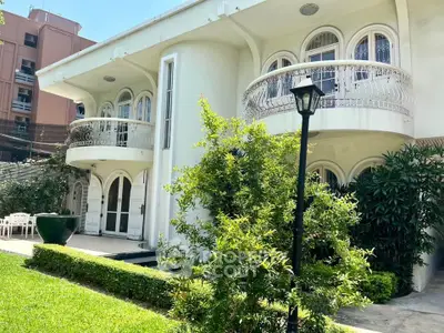 Elegant two-story building with lush garden and unique arched windows