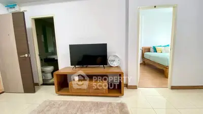 Spacious living room with modern TV stand and view into cozy bedroom