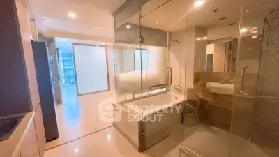 Modern apartment interior with glass-enclosed bathroom and cozy bedroom.