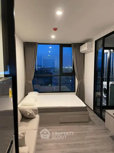 Modern bedroom with large window and city view, featuring a cozy bed and stylish decor.