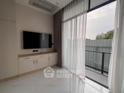Modern living room with TV and balcony view, featuring sleek design and natural light.