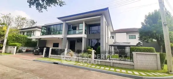 Modern two-story house with large windows and landscaped front yard in a suburban neighborhood.