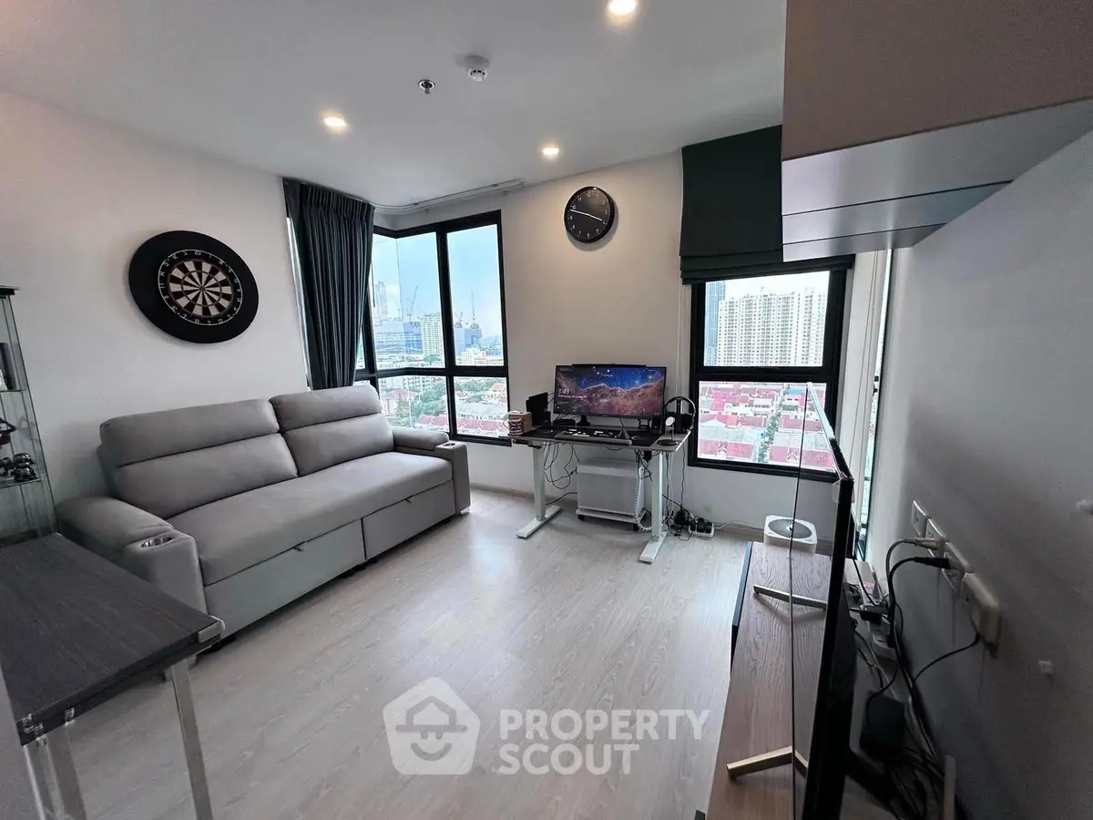 Modern living room with city view, featuring sleek furniture and entertainment setup.