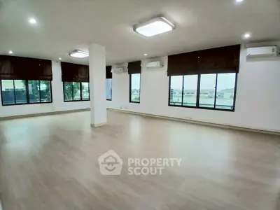 Spacious open-plan living room with large windows and modern lighting in a bright apartment.