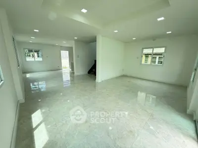 Spacious open-plan living room with large windows and glossy tiled floors