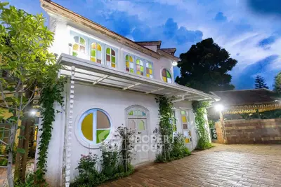 Charming two-story house with colorful stained glass windows and lush greenery, perfect for serene living.