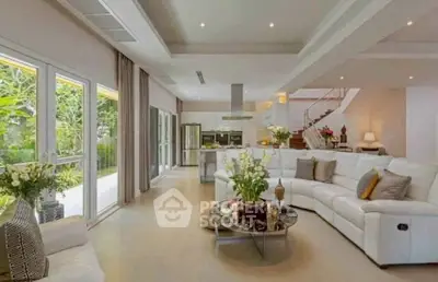 Spacious modern living room with open kitchen and garden view, featuring elegant decor and ample natural light.