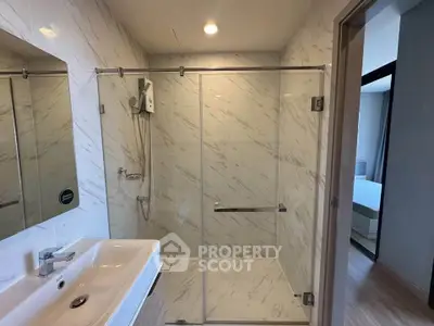 Modern bathroom with glass shower enclosure and sleek sink in a contemporary apartment.