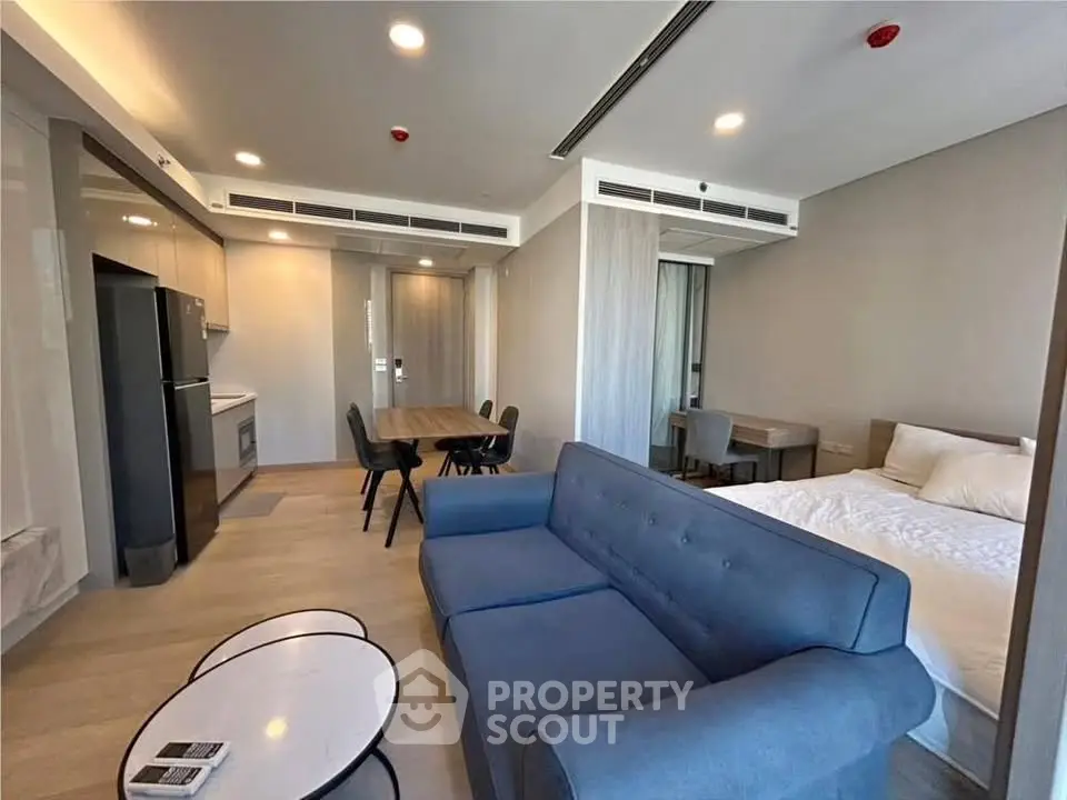 Modern studio apartment with open layout, featuring a cozy living area, dining space, and sleek kitchen.