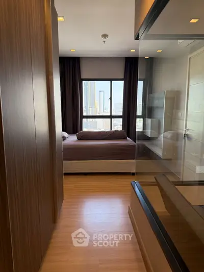 Modern bedroom with city view and glass partition, featuring sleek wooden flooring and contemporary design.