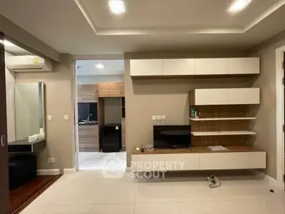 Modern living room with sleek built-in storage and TV unit, featuring neutral tones and stylish lighting.