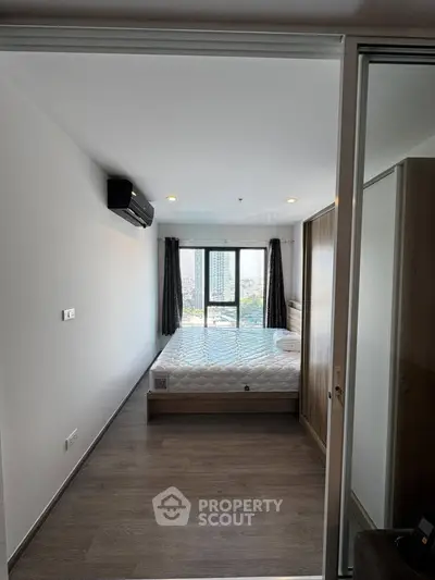 Modern bedroom with large window and city view, featuring sleek wooden flooring and minimalist design.