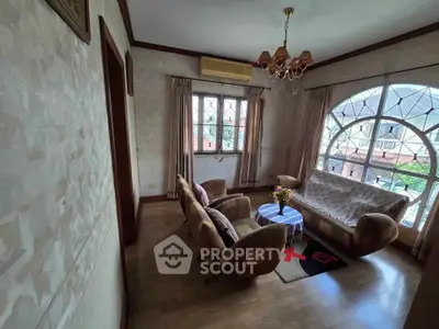 Charming living room with vintage furniture and large windows offering natural light.