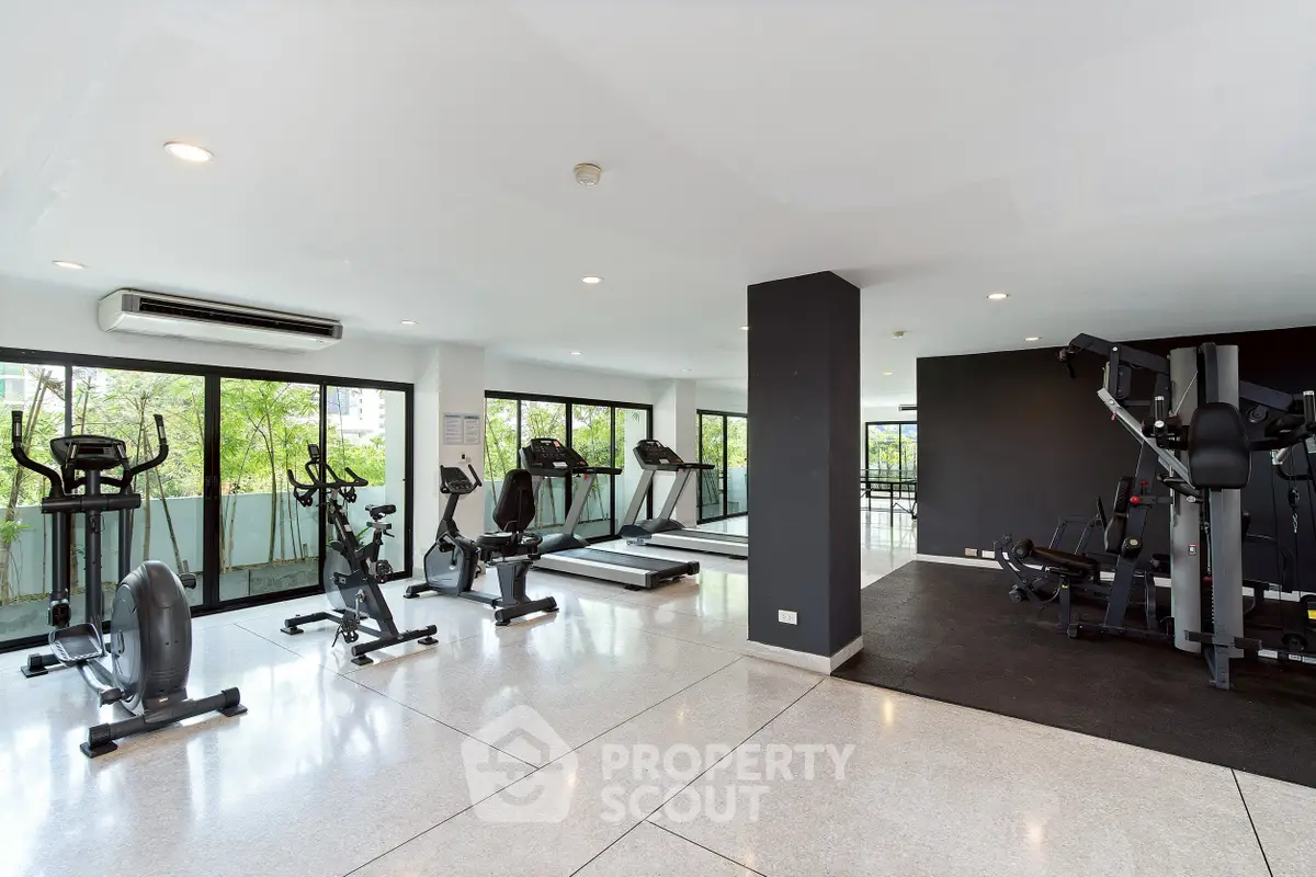 Spacious modern gym with large windows and fitness equipment in a residential building.