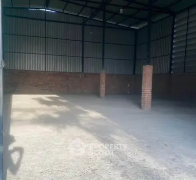 Spacious industrial warehouse with high ceilings and brick walls, ideal for storage or manufacturing.