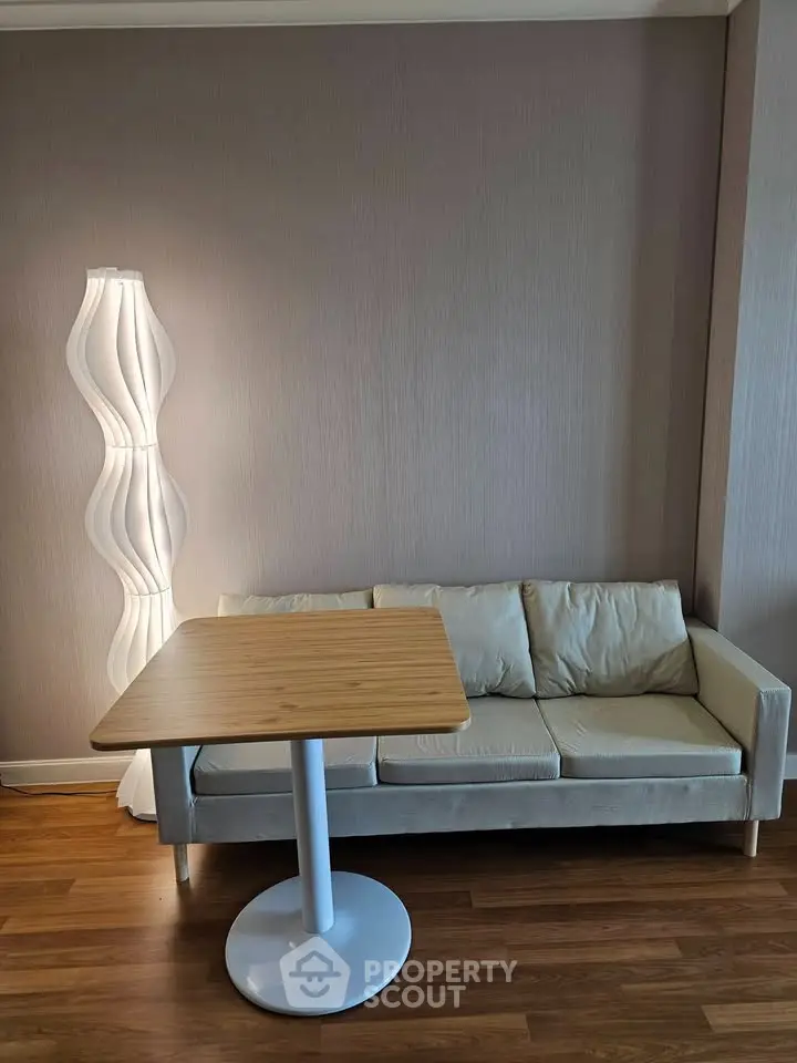Modern living room with stylish sofa, unique floor lamp, and wooden table on elegant hardwood flooring.