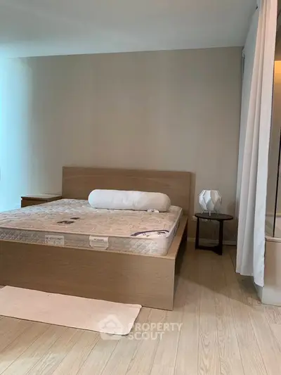 Spacious bedroom with modern wooden bed and stylish lamp, perfect for a cozy retreat.