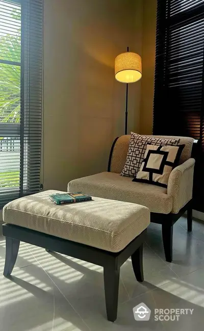 Cozy reading nook with elegant armchair and ottoman by sunlit window