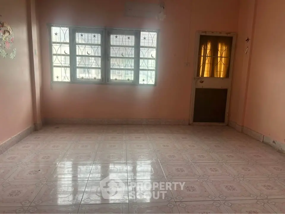 Spacious empty room with tiled floor and large windows, ideal for customization.