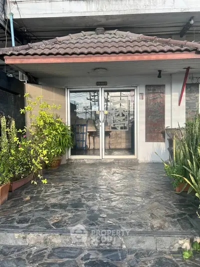 Charming entrance with stone steps and lush greenery leading to a cozy building.