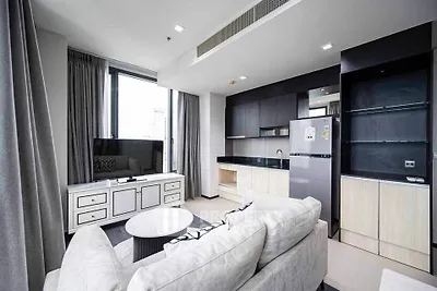 Modern living room with sleek design, featuring a cozy sofa, large window, and stylish kitchen area.