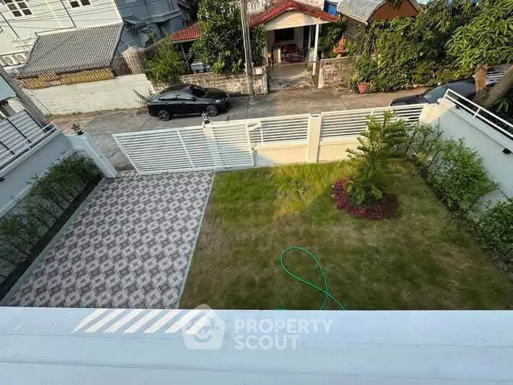 Charming residential garden with lush greenery and paved area, perfect for outdoor relaxation.