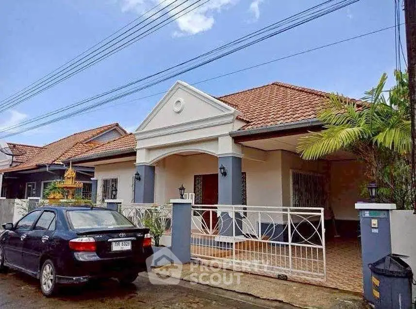 Charming single-story house with tiled roof and gated entrance in a suburban neighborhood.
