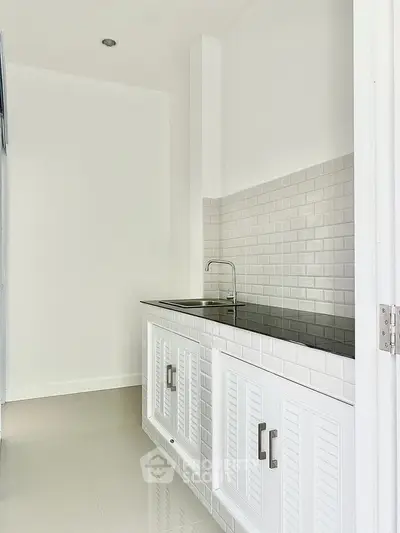 Modern minimalist kitchen with sleek white cabinetry and tiled backsplash