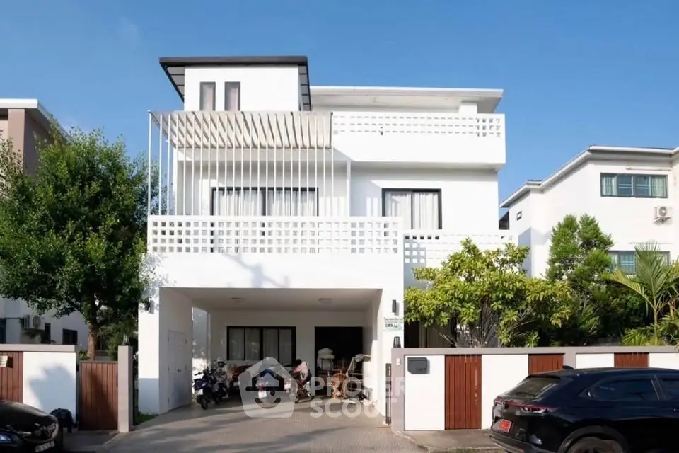 Modern white three-story house with spacious driveway and lush greenery