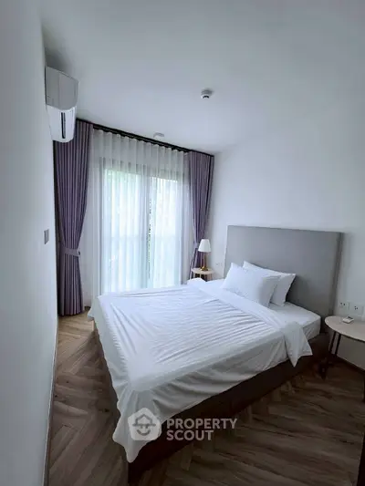 Modern bedroom with elegant decor, featuring a cozy bed, stylish curtains, and natural light through large windows.