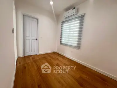 Spacious bedroom with wooden flooring and modern air conditioning unit.