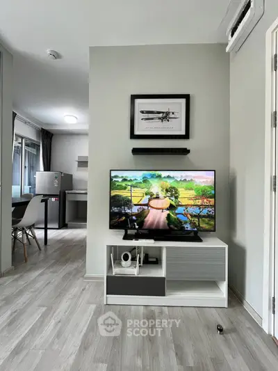 Modern living room with sleek TV stand and open kitchen layout in stylish apartment.