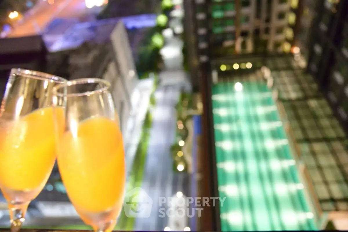 Luxurious high-rise view with sparkling pool and city lights, perfect for urban living.