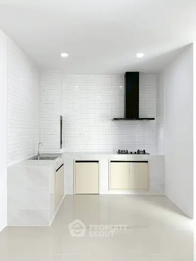 Modern minimalist kitchen with sleek white tiles and gas stove