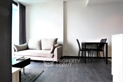 Modern living room with stylish sofa and dining area, featuring sleek flooring and natural light.