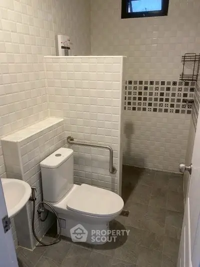 Modern bathroom with tiled walls and accessible toilet design.