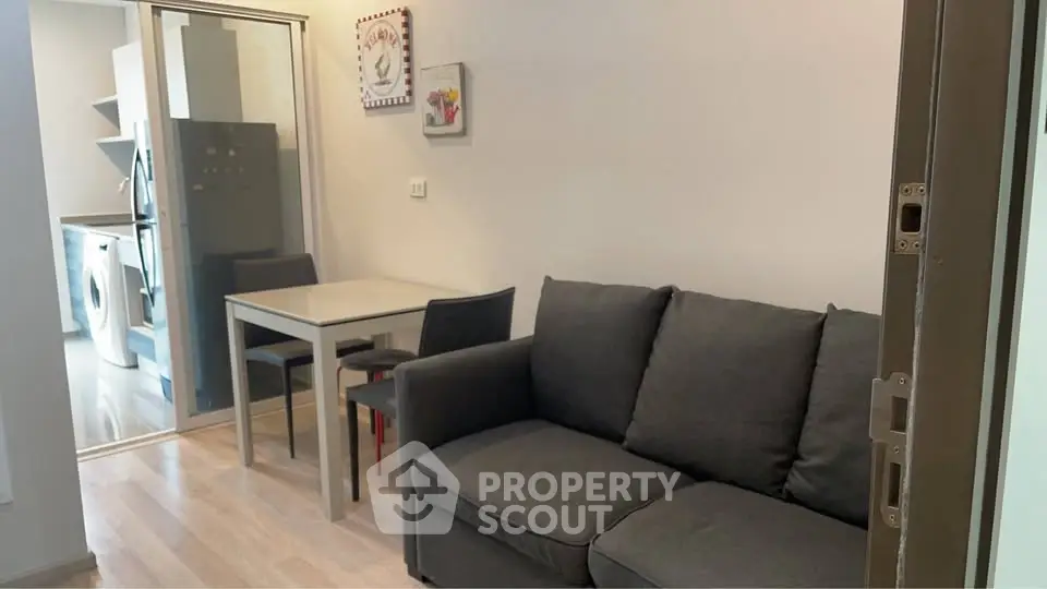 Modern living room with cozy sofa and dining area, adjacent to a sleek kitchen with appliances.