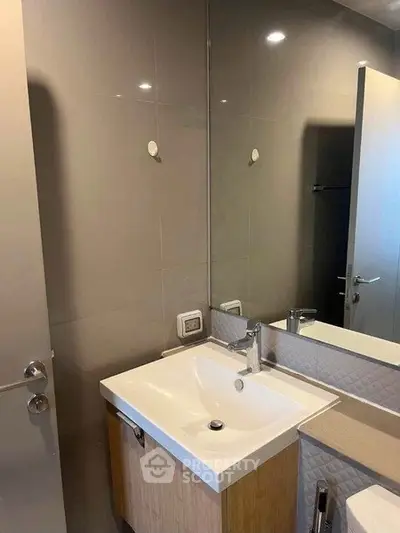 Modern bathroom with sleek sink and large mirror in contemporary apartment.