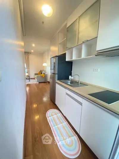 Modern kitchen with sleek cabinetry and open layout leading to cozy living area.