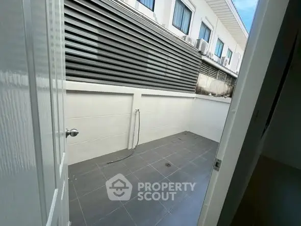 Spacious outdoor area with tiled flooring and privacy wall, perfect for versatile use.