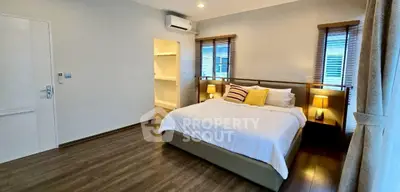 Spacious bedroom with modern decor and natural light, featuring a cozy bed and elegant wooden flooring.