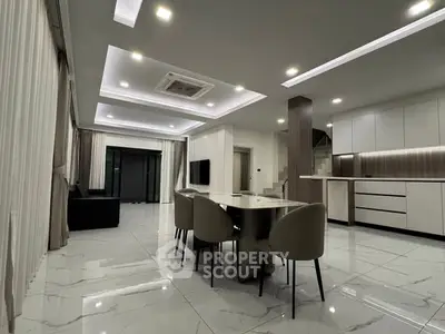 Modern open-plan living and dining area with sleek kitchen design and elegant lighting.