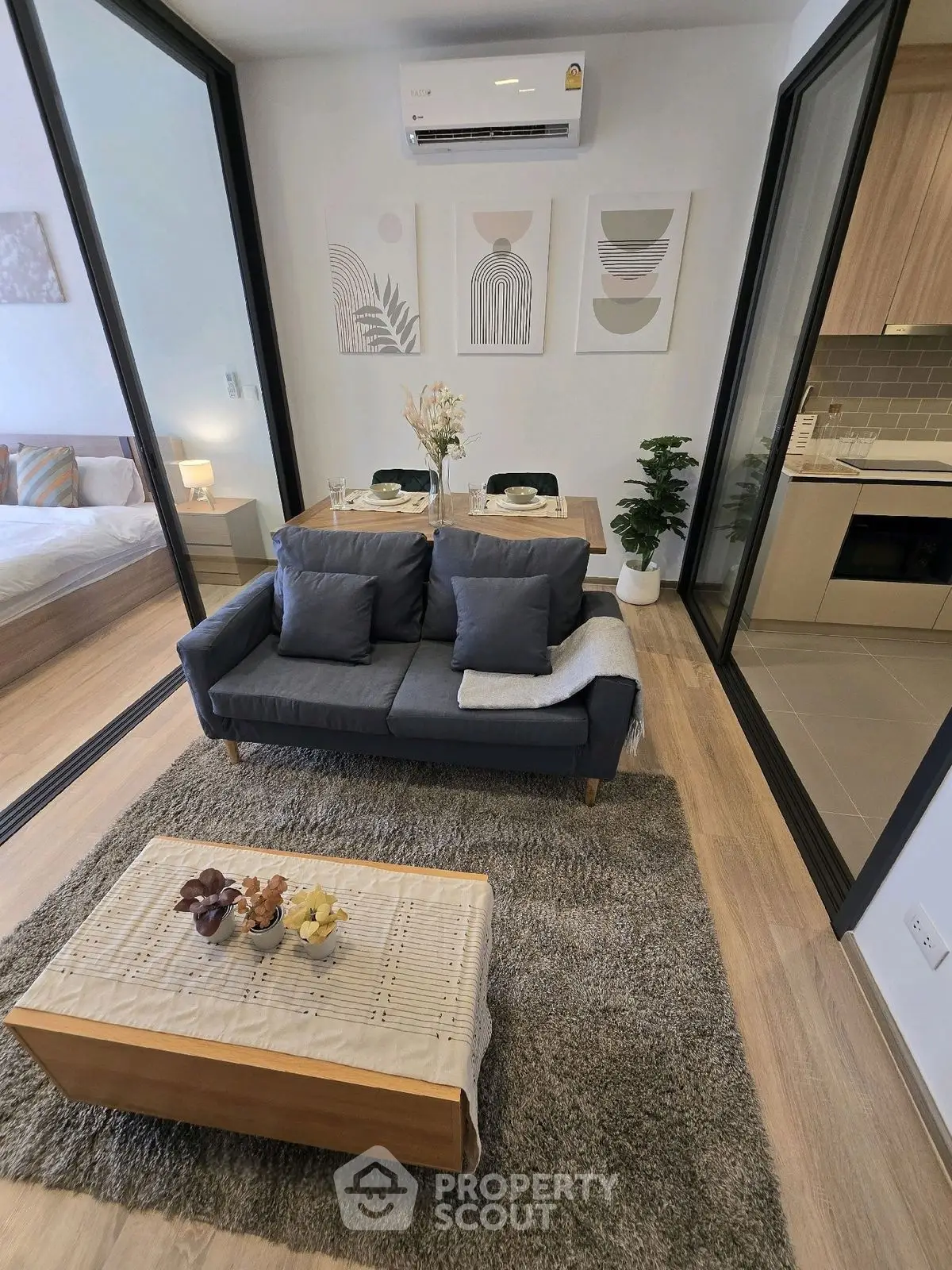 Modern living room with cozy sofa, dining area, and stylish kitchen in open layout apartment.