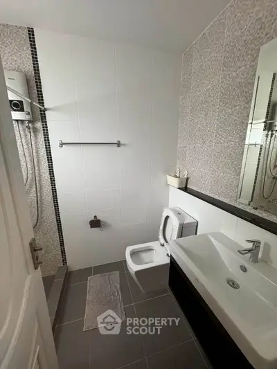 Modern bathroom with sleek fixtures and stylish tile design, featuring a spacious shower area and contemporary sink.