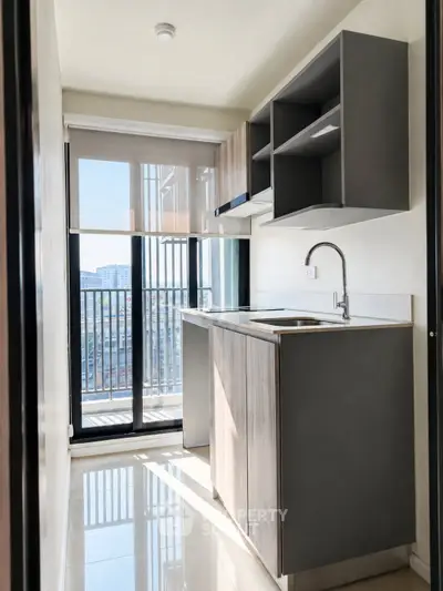 Modern kitchen with sleek cabinetry and balcony view in a stylish apartment.