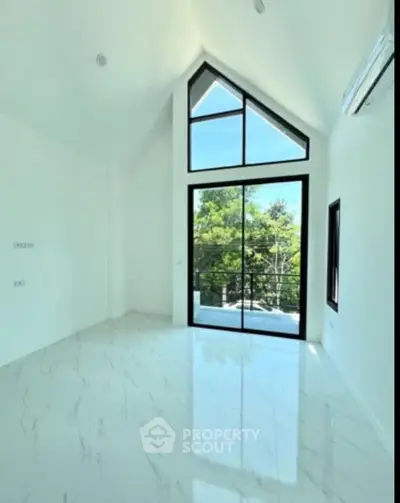 Bright and airy room with high ceiling and large windows offering scenic views.