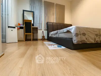Cozy bedroom with modern decor and wooden flooring, featuring a stylish bed and a compact study area.